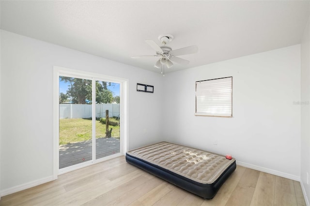 bedroom with baseboards, wood finished floors, a ceiling fan, and access to exterior