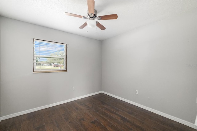 empty room featuring baseboards, dark wood finished floors, and a ceiling fan