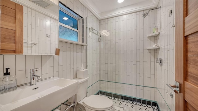 bathroom with tiled shower, a sink, and tile walls