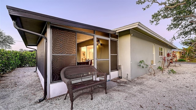 back of property featuring a sunroom and stucco siding