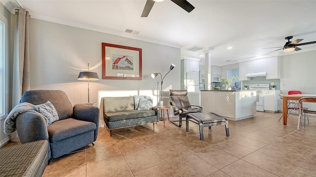 living area featuring ceiling fan, light tile patterned flooring, visible vents, and ornate columns