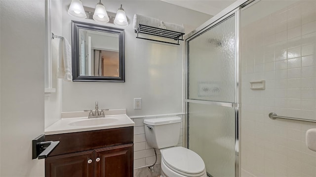 bathroom with toilet, a shower stall, and vanity