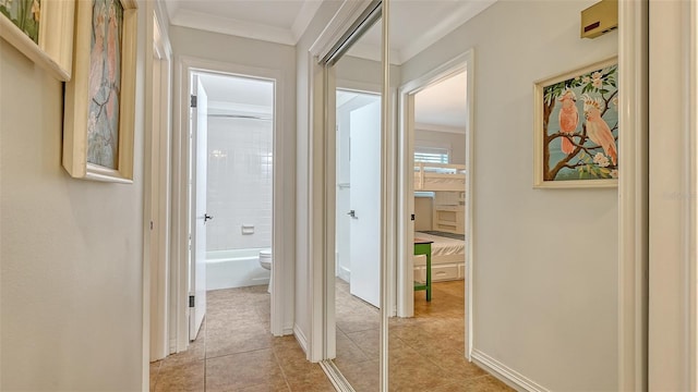 hall featuring light tile patterned floors, ornamental molding, and baseboards