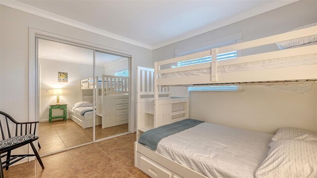 bedroom with crown molding, a closet, and light tile patterned flooring