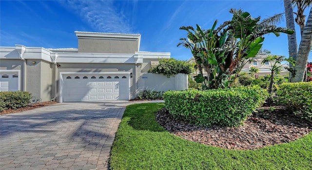 view of front facade with a garage, decorative driveway, and stucco siding