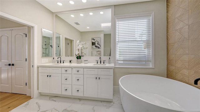 bathroom featuring a soaking tub, recessed lighting, double vanity, and marble finish flooring