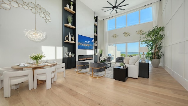3540 Mistletoe Ln, Longboat Key, FL 34228 - living area featuring light wood-style floors, a towering ceiling, a chandelier, built in features, and a glass covered fireplace