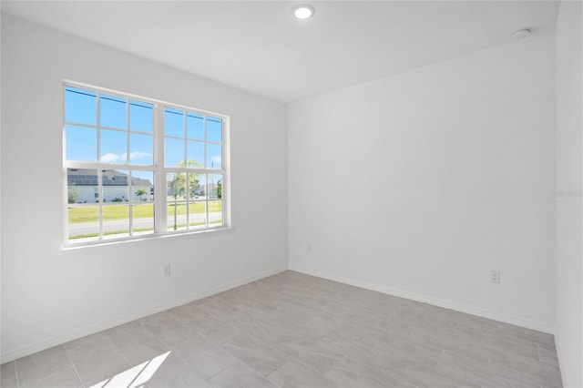 spare room featuring recessed lighting and baseboards