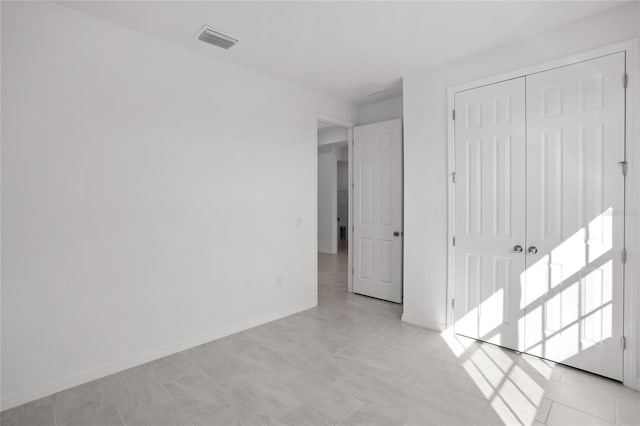 unfurnished bedroom with a closet, visible vents, and baseboards