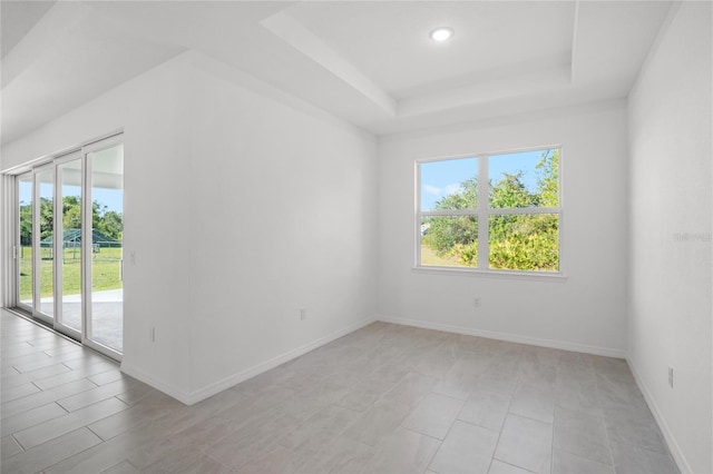 unfurnished room with a tray ceiling, recessed lighting, and baseboards