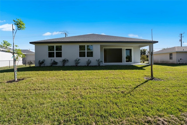 back of house with fence, a lawn, and stucco siding