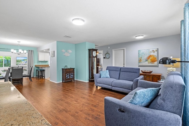 living area featuring visible vents, dark wood finished floors, baseboards, and an inviting chandelier