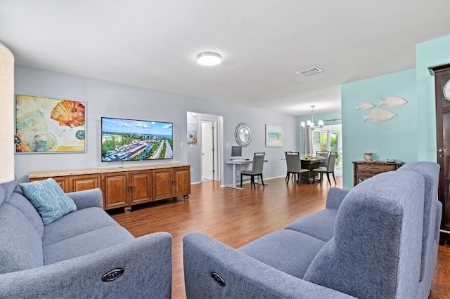 living room featuring baseboards, dark wood-style flooring, visible vents, and an inviting chandelier