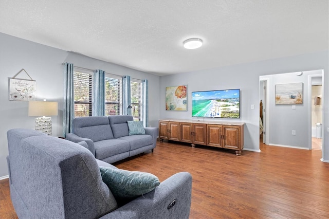 living room featuring a textured ceiling, wood finished floors, and baseboards