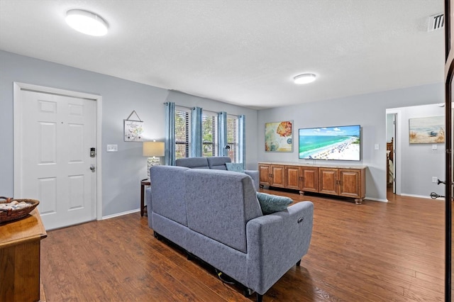 living room with dark wood-style floors, visible vents, a textured ceiling, and baseboards