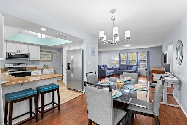 dining area with a chandelier, visible vents, light wood-style flooring, and baseboards