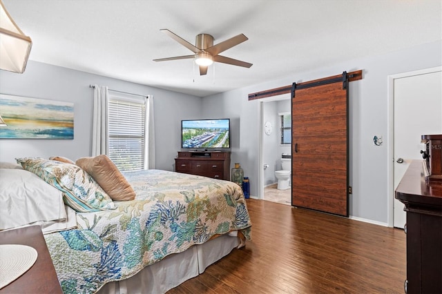 bedroom featuring ceiling fan, a barn door, connected bathroom, baseboards, and dark wood-style floors