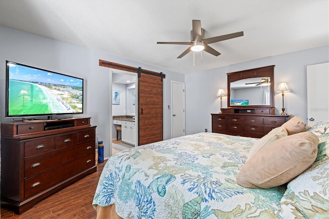 bedroom with a barn door, connected bathroom, a ceiling fan, and wood finished floors