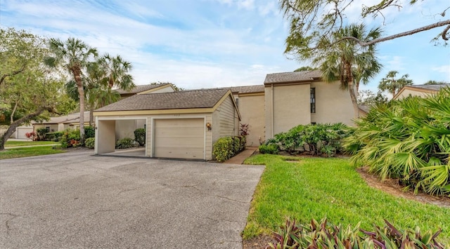 view of front of property with a garage, driveway, a front lawn, and stucco siding