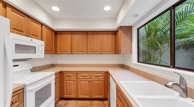 kitchen featuring brown cabinets, white appliances, a sink, and a healthy amount of sunlight