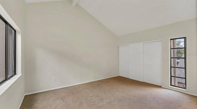 unfurnished bedroom with high vaulted ceiling, a closet, carpet flooring, and beam ceiling