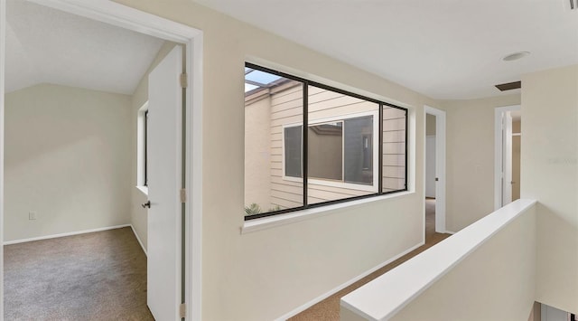 hall featuring carpet floors, lofted ceiling, baseboards, and an upstairs landing