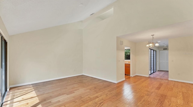 spare room with a chandelier, baseboards, lofted ceiling, and light wood-style floors