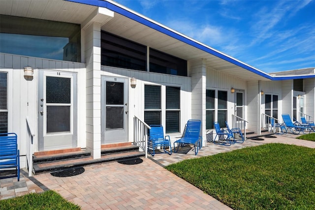 property entrance with a lawn and a patio