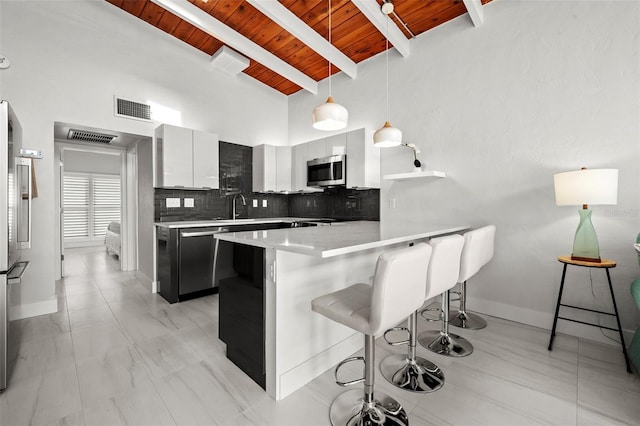 kitchen featuring a breakfast bar, stainless steel appliances, light countertops, white cabinets, and modern cabinets