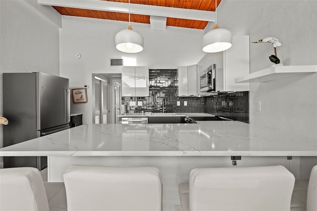 kitchen with appliances with stainless steel finishes, modern cabinets, decorative light fixtures, and white cabinets