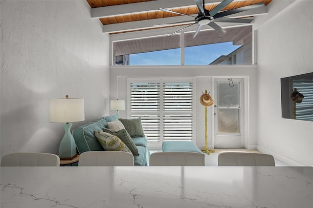 living area with wooden ceiling, a ceiling fan, beam ceiling, and a textured wall