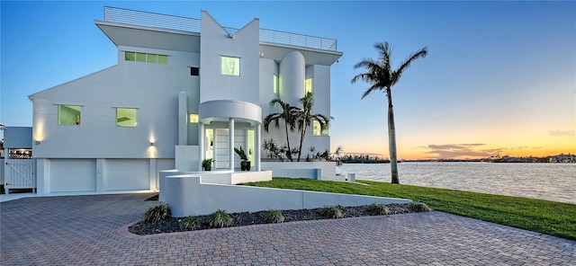 view of front of home featuring a water view, a garage, decorative driveway, and stucco siding