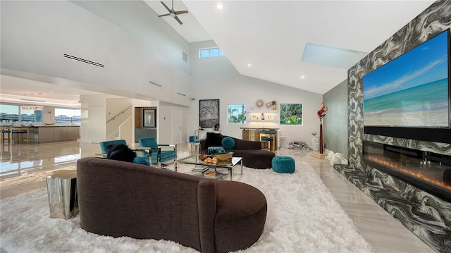 living room featuring a large fireplace, a high ceiling, and visible vents