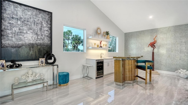 bar featuring beverage cooler, baseboards, lofted ceiling, wet bar, and a sink