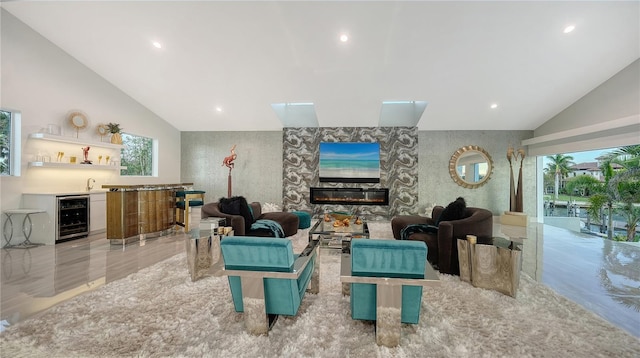 living area featuring beverage cooler, plenty of natural light, a glass covered fireplace, and wet bar