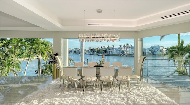 sunroom with a water view, visible vents, and a tray ceiling