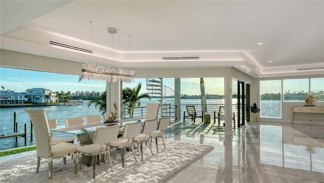 dining space featuring a tray ceiling, a water view, and visible vents