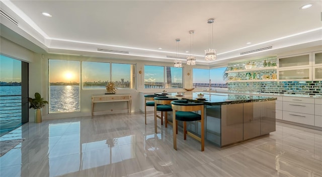 kitchen featuring white cabinets, decorative backsplash, modern cabinets, a center island, and hanging light fixtures