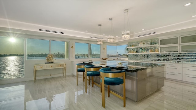 kitchen with a breakfast bar, a kitchen island, backsplash, open shelves, and modern cabinets