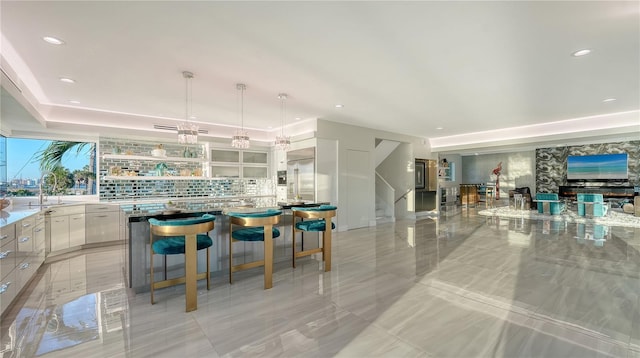 kitchen with recessed lighting, light countertops, hanging light fixtures, white cabinetry, and a sink