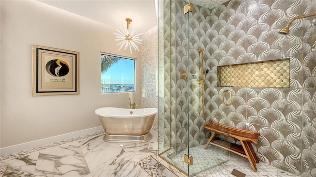 full bath featuring a chandelier, marble finish floor, a soaking tub, and baseboards