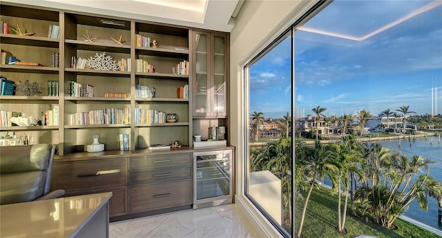 interior space with beverage cooler, marble finish floor, and a water view