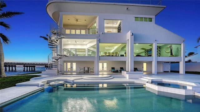 rear view of property featuring french doors, a patio, stucco siding, a pool with connected hot tub, and a balcony