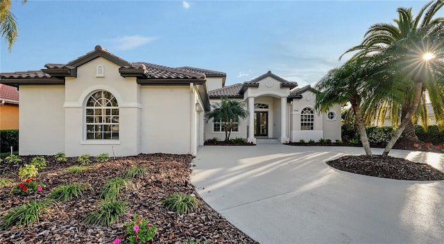 mediterranean / spanish house featuring concrete driveway, a tile roof, and stucco siding