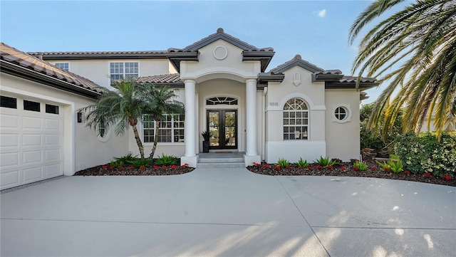 view of exterior entry featuring an attached garage, stucco siding, a tile roof, and french doors