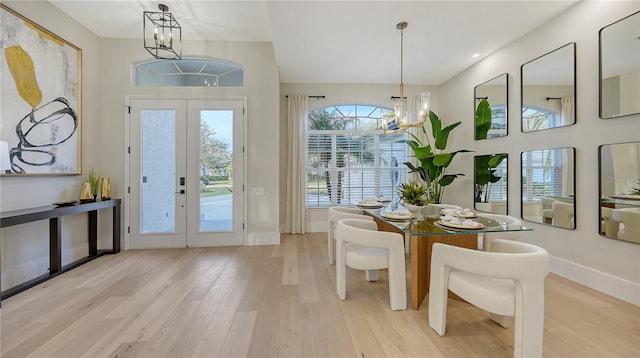 interior space with french doors, a high ceiling, a chandelier, light wood-type flooring, and baseboards