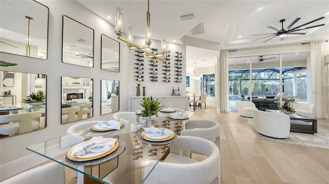 dining space with ceiling fan, light wood-style flooring, a fireplace, a sunroom, and visible vents