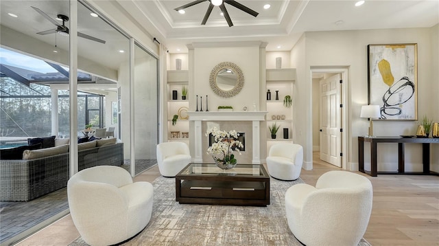 interior space featuring built in shelves, a fireplace, a ceiling fan, and crown molding