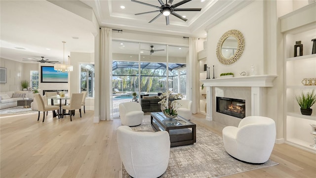 living area featuring ornamental molding, a sunroom, built in features, and wood finished floors