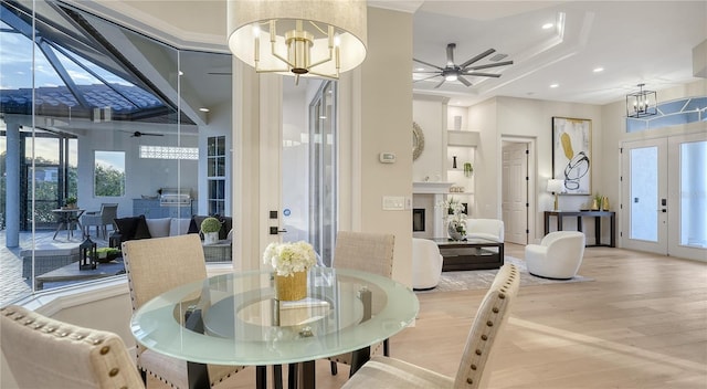 dining area with recessed lighting, ceiling fan with notable chandelier, wood finished floors, french doors, and a glass covered fireplace